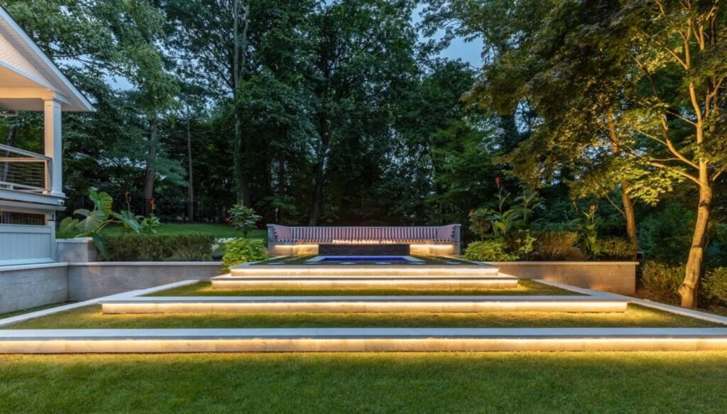 Illuminated steps through lawn and planting at dusk.